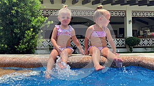 small triplets sisters playing in the pool in swimsuits