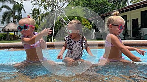 small triplets sisters playing in the pool in swimsuits