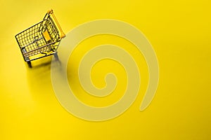 Small trolley in a yellow background. Black Friday and Cybermonday concept