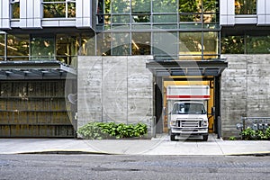 Small truck with big box trailer for moving use standing at the apartment building gate dock unloading delivered cargo photo