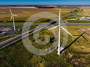 Small truck rides on big road and huge wind turbines blue clear sky background, generating electricity along