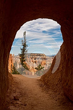 A small tunnel cutting through the sandstone a the stunning Bryce Canyon at the end of the tunnel is a view out across the canyon