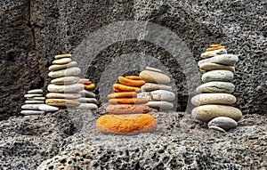 small turrets among rocks , flat stones stacked in little towers on black rock background , immersive travel concept landscape