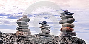 small turrets on a sea coast, flat stones stacked in little towers on ocean beach with water and blue sky background , immersive