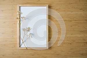 Small twig of gypsophila on an empty picture frame on a bamboo background, still life and home decor in minimalist Japandi style, photo