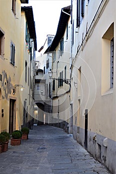 Small typical cross between buildings with arched door in the center of Pistoia.