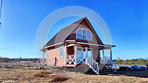 A small unfinished country house in the middle of a field. Building a new cottage in nature in the spring with good