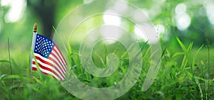 Small USA flag outside in rural grassland. Patriotic American flag symbolizing the United States of America for 4th of July,