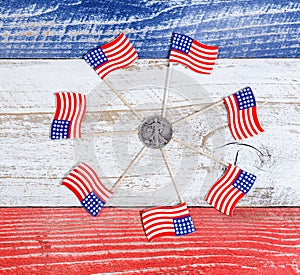 Small USA flags in circle formation around Liberty coin on rustic boards with national colors