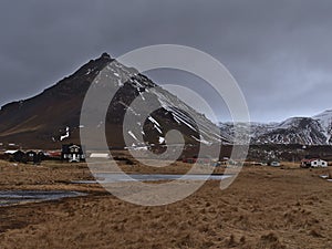 Small village Arnarstapi, part of SnÃ¦fellsbÃ¦r, on the coast of SnÃ¦fellsnes, Iceland on cloudy winter day with frozen lake.
