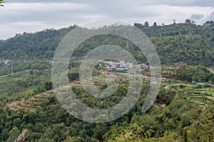 Small village at beautiful green wide valley view landscape among mountains covered with trees under cloudy sky