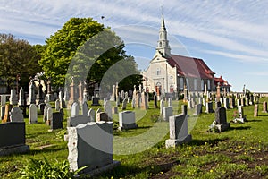 Small village cemetery and patrimonial neoclassical 1737 stone catholic church in Saint-Jean, Island of Orleans