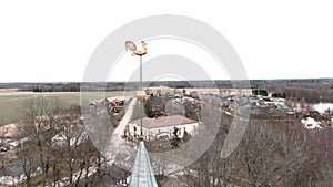 Small village church with golden weather vane cockerel on top of bell tower in Umurga, Latvia. Aerial view from drone