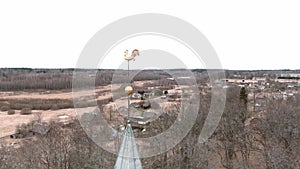 Small village church with golden weather vane cockerel on top of bell tower in Umurga, Latvia. Aerial view from drone