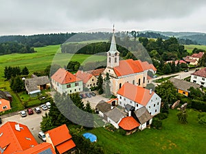 Small village in the middle of meadow, wood and hill, aerial view
