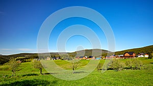 Small village of mountain huts in a green colorful hilly landscape with Snezka mountain in the background, Pomezni Boudy, Krkonose photo