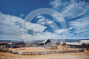 a small village under a blue sky, with snow-capped mountains in the background. Old houses. Russia, Siberia, Arshan