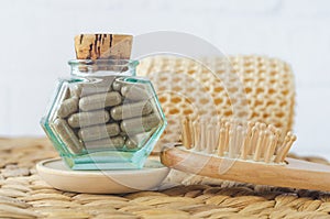 Small vintage bottle with food supplement capsules and wooden hairbrush. Natural healthcare, herbal medicine