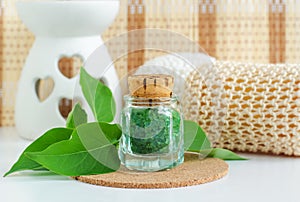 Small vintage glass bottle with green bath salts epsom salt, foot soak and green fresh leaves. Copy space