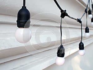 small vintage light bulb hanging around white concrete wall