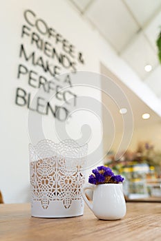 Small violet flower in a white cupin a white vintage cafe