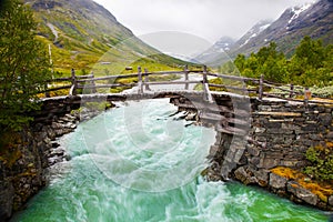 Small walk bridge over green river in Norway