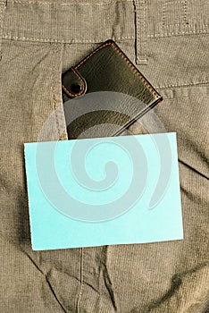 Small wallet in the trousers front pocket beside blue note sheet. Little purse is placed inside man pants near notation