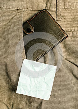 Small wallet in the trousers front pocket beside blue note sheet. Little purse is placed inside man pants near notation