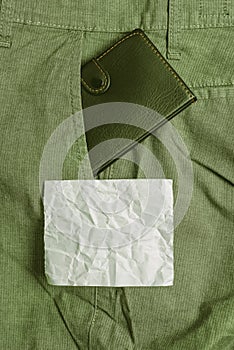 Small wallet in the trousers front pocket beside purple note sheet. Little purse is placed inside man pants near