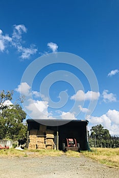 Small warehouse with tractors and straw. Vertical.