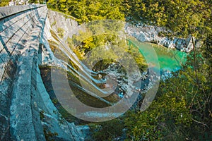 Small water dam of Podselo in river Soca close to Most na Soci, water dam surrounded by lush green and white chalk rock on a