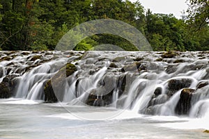 Small waterfall in the beautiful Dobra river surrounded by green nature, located in Croatia