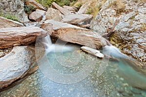 Small waterfall casdcading over rocks in blue pond