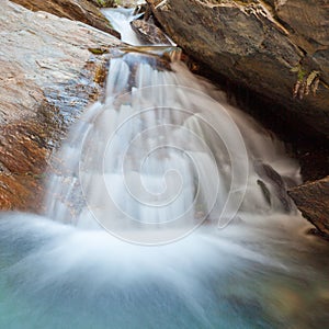 Small waterfall casdcading over rocks in blue pond