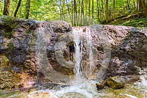 Clear water of a brook, flows over an old dam, built as torrent control