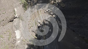 Small waterfall flowing down the rock in the Swiss Alps filmed by drone
