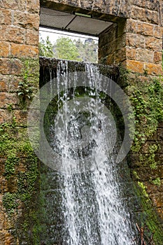 A small waterfall is flowing down a stone wall
