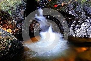 Small waterfall flowing over rocks in nature.