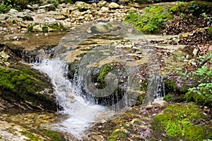 A small waterfall that flows over the boulders of a stream (Italy, Europe)