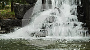 Small waterfall flows into a pond. rushing stream water