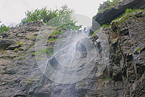 small waterfall that flows from road parapet.