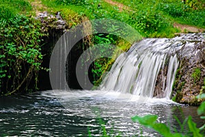 A small waterfall in the forest. Bright juicy greens and splashes of water. A quiet and peaceful place for family holidays