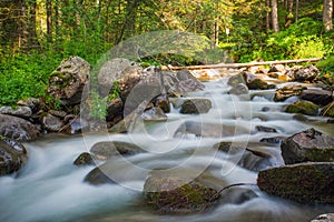 Small waterfall in a forest river with silky water around the rocks in the stream. Long exposure