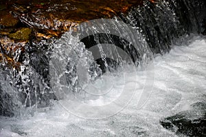 A small waterfall. The height difference of the water flow in the river is equipped with round wooden logs.