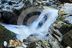 Small waterfall in a mountain stream between rocks, the water is blurred in motion