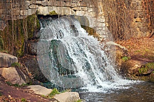 Small waterfall in an old building in an autumn park