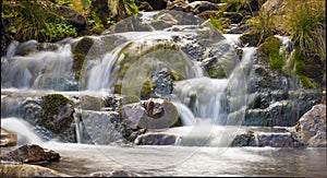 Small Waterfall in park with beautifull smooth water. Little waterfall in mountain forest with silky foaming water.