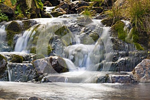 Small Waterfall in park with beautifull smooth water. Little waterfall in mountain forest with silky foaming water.