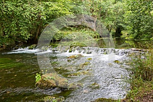 Small waterfall on River Dove running through steep hills in Dovedale