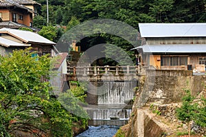 Small waterfall in river through village in Japanese countryside